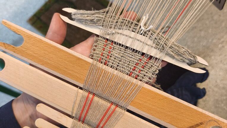 Close-up of a hip loom weaving fabric.